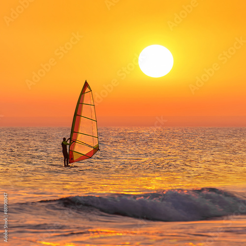 Windsurfer silhouette at sea sunset. Summertime watersports 