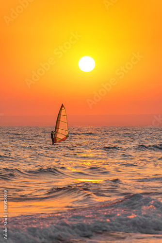Windsurfer silhouette at sea sunset. Summertime watersports 