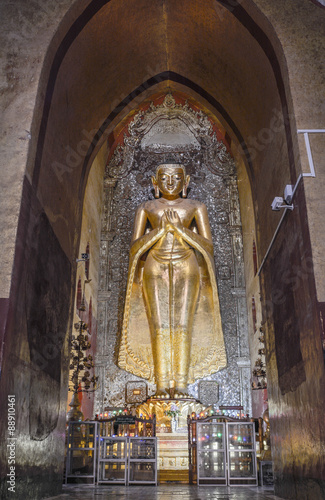 tanding Buddha Kassapa at the Ananda temple adorned by believers by sticking golden leaves on statue in Bagan, Myanmar.