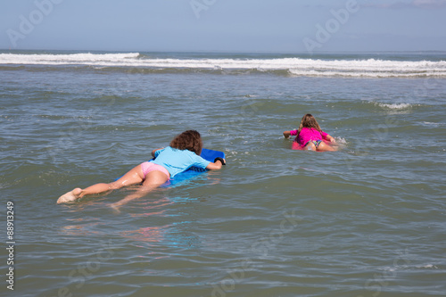 On holidays at the ocean, children have fun  surfing with bodyboard photo