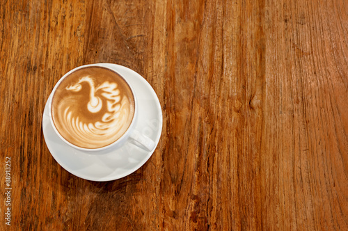 Hot cafe latte wirh latte art on wooden table