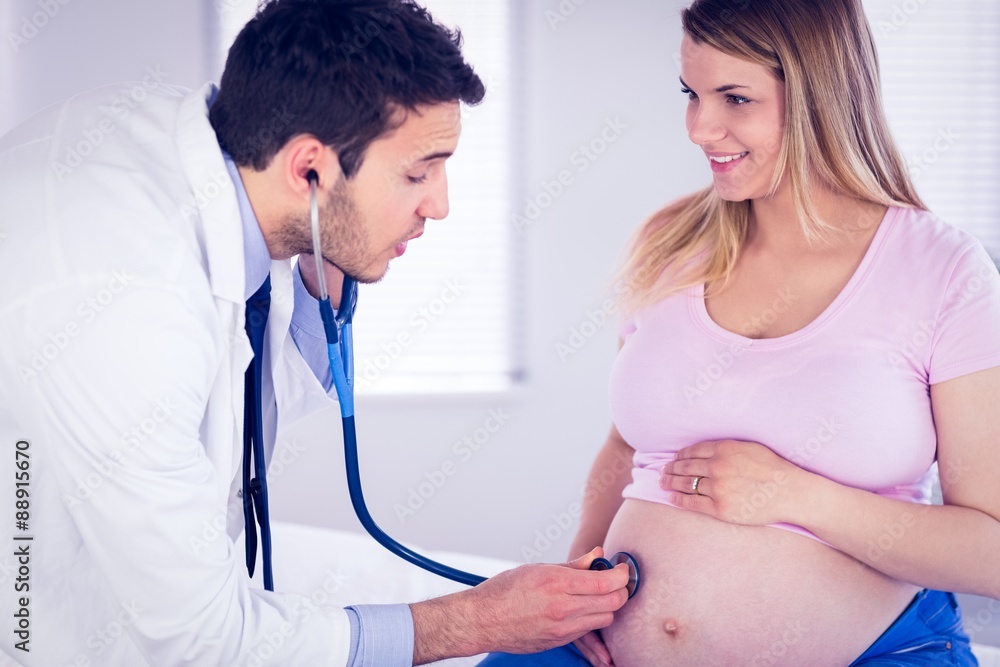 Doctor talking to smiling pregnant patient while examining her Doctor talking to smiling pregnant patient while examining her