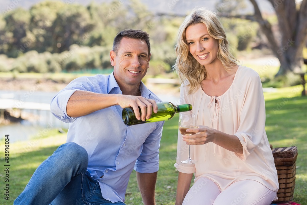 Portrait of smiling couple sitting and pouring wine in glass Portrait of smiling couple sitting and pouring wine in glass