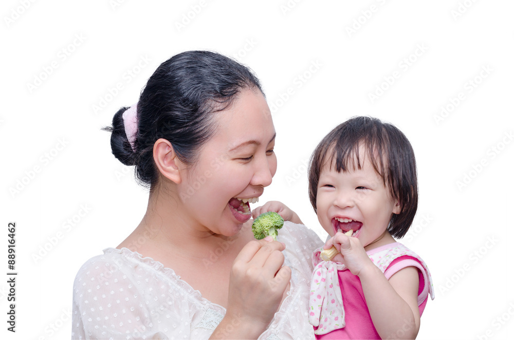 Asian mother and her daughter eating vegetables over white Asian mother and her daughter eating vegetables over white