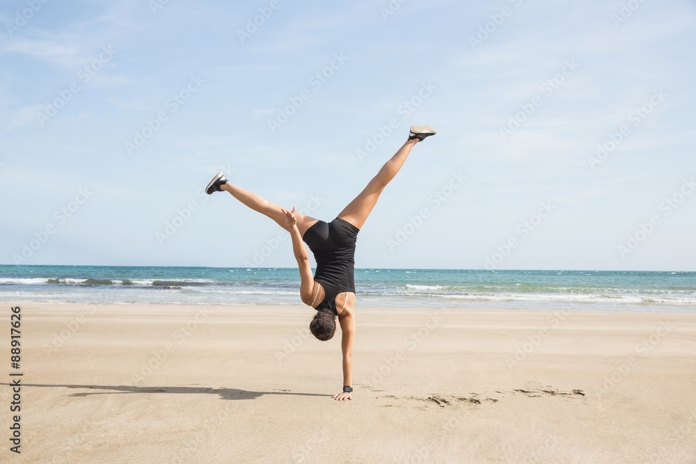 Fit woman cartwheeling on the sand Fit woman cartwheeling on the sand
