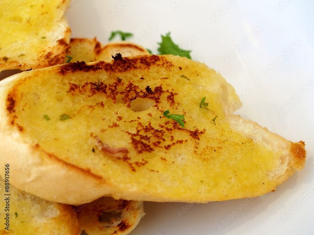 Close-up of a garlic bread on the white dish.