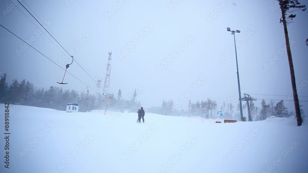 Skiers going down the slope near ski lift in mountains Skiers going down the slope near ski lift in mountains