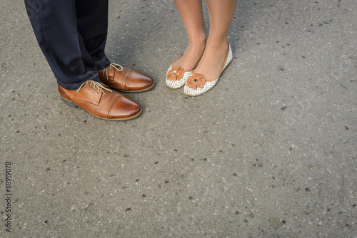The feet of a dressed up wedding couple with blank space on the street for save the date or wedding invitation text.