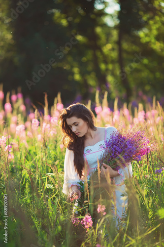 Beautiful young girl, holding lavender in a field on sunset. wal