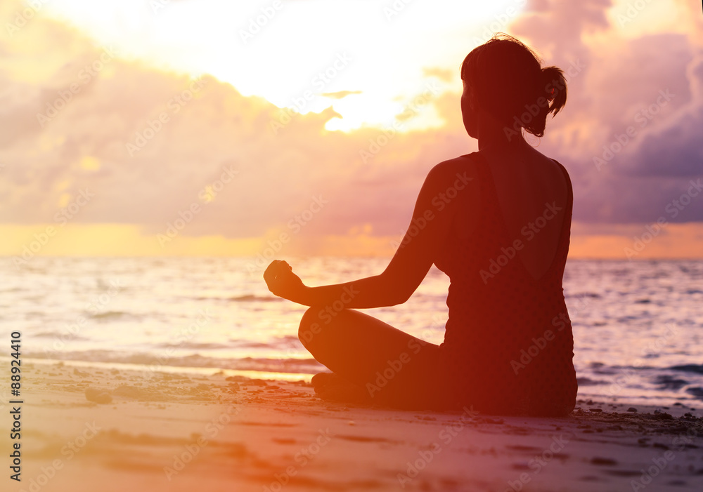 Woman meditation on sunset beach