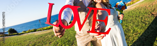 Fotografie bride with groom holding bouquet and word love