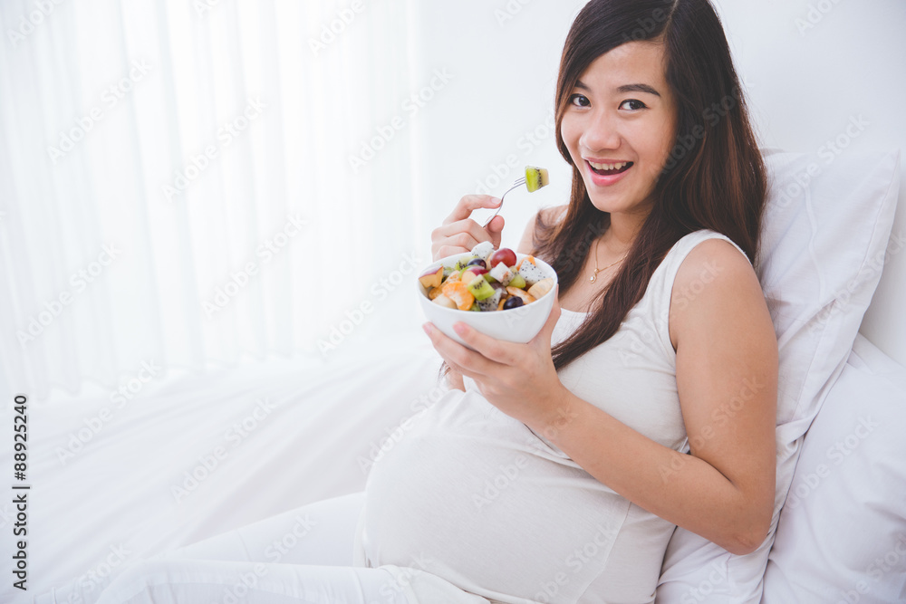 Beautiful pregnant woman with a bowl of fruit, white background Beautiful pregnant woman with a bowl of fruit, white background
