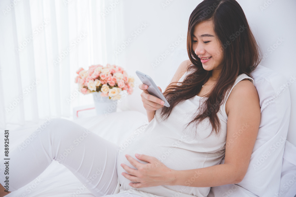 Beautiful pregnant asian woman using a smartphone Beautiful pregnant asian woman using a smartphone