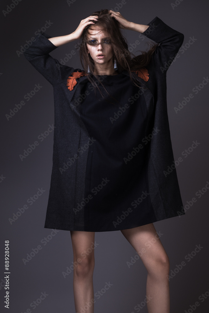 Stylish girl in a fashionable autumn clothes and bright make-up with the wind in her hair. Picture taken in the studio on a gray background. Stylish girl in a fashionable autumn clothes and bright make-up with the wind in her hair. Picture taken in the studio on a gray background.