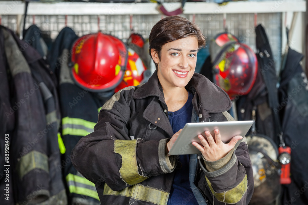 Obraz premium Happy Firewoman Holding Digital Tablet At Fire Station