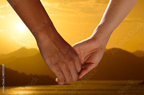 Couple holding hands watching a beautiful sunset