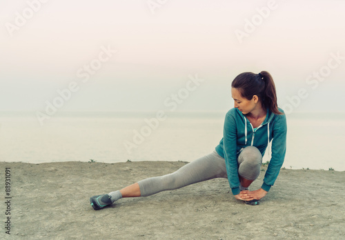 Girl stretching her legs on coast, wokout