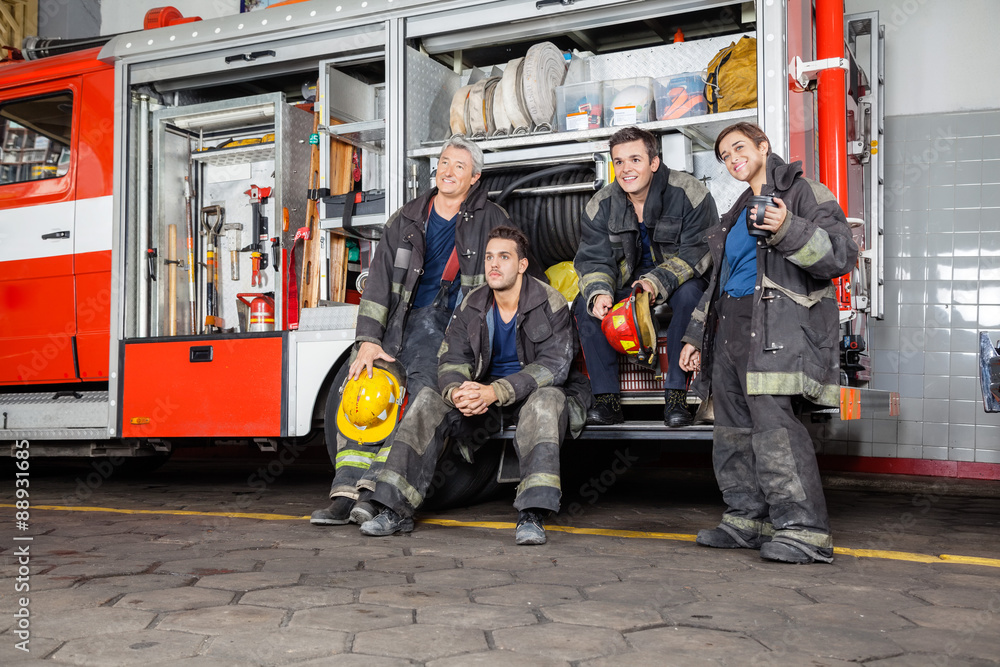 Obraz premium Team Of Thoughtful Firefighters By Firetruck
