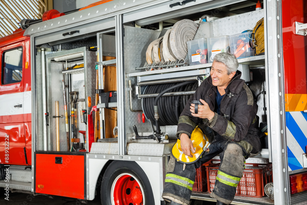 Fototapeta premium Happy Fireman Sitting In Truck At Fire Station