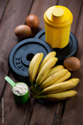 Weight plates, shaker and protein, bunch of bananas and hen eggs