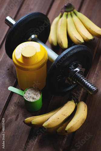 Dumbbell, plastic shaker, measuring scoop of protein and bananas