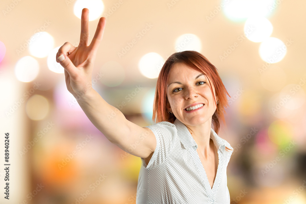 Young woman doing victory gesture over white background Young woman doing victory gesture over white background