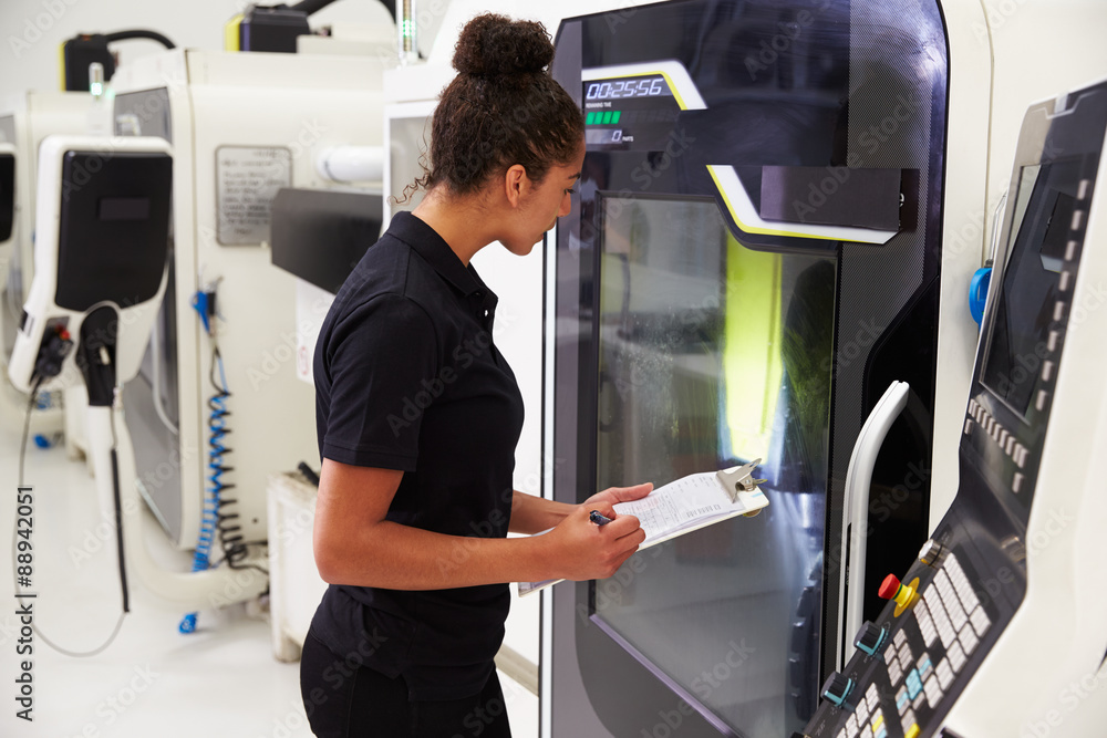 Female Engineer Operating CNC Machinery On Factory Floor Female Engineer Operating CNC Machinery On Factory Floor