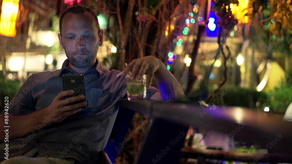 Young man using smartphone and drinking beverage in cafe at night
Young man using smartphone and drinking beverage in cafe at night