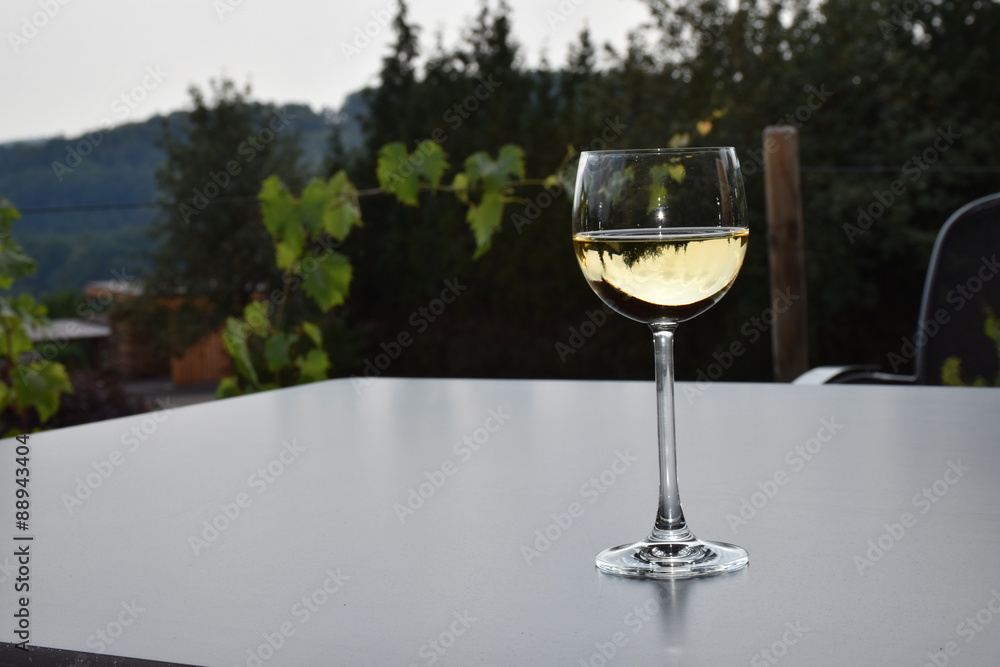 Weißwein im Glas, auf grauem Tisch, Hintergrund grün Weißwein im Glas, auf grauem Tisch, Hintergrund grün