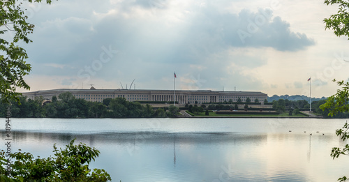 The Pentagon, headquarters of the Department of Defense, behind and reflected in the Pentagon Lagoon Yacht Basin with storm clouds developing in the sky  and the sun's rays peeking through. photo