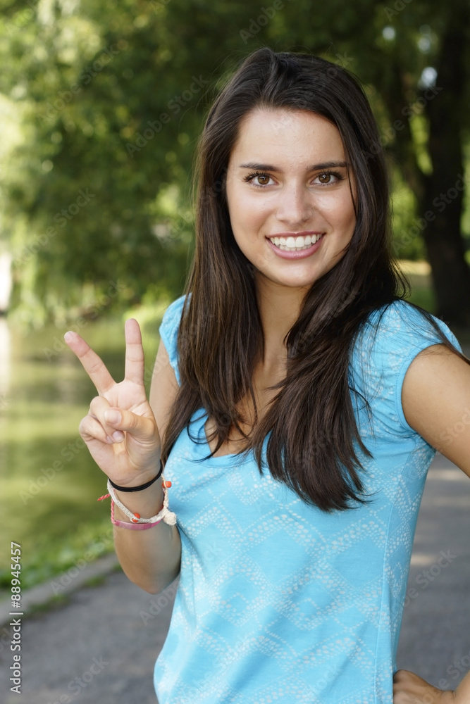 An attractive young woman smiles and gives the peace sign. An attractive young woman smiles and gives the peace sign.