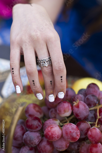Fotografi Young woman is holding fresh grapes near the salver with apple, pear