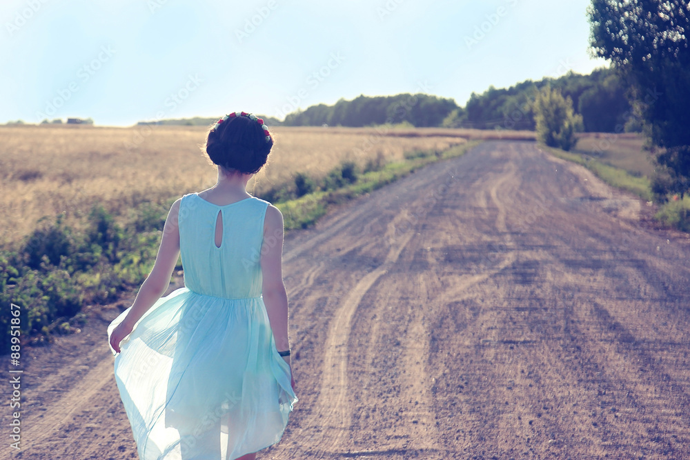 Romantic girl walking on the village road. Young girl in the blue silk dress Romantic girl walking on the village road. Young girl in the blue silk dress