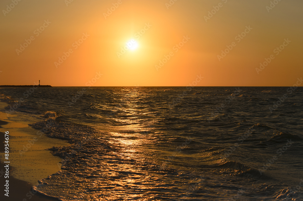 Stunning golden sunset at the beach with sea waves 
