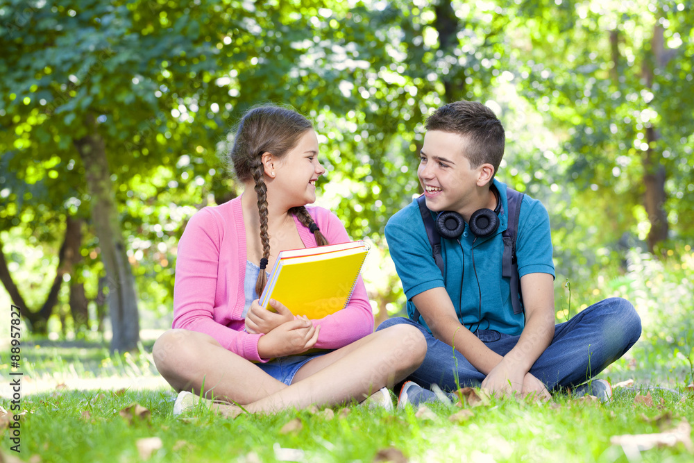 Smart kids sitting on the grass looking happy Smart kids sitting on the grass looking happy