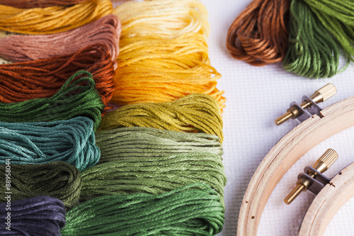 Tablou pe pânză Embroidery yarns and hoops on fabric background