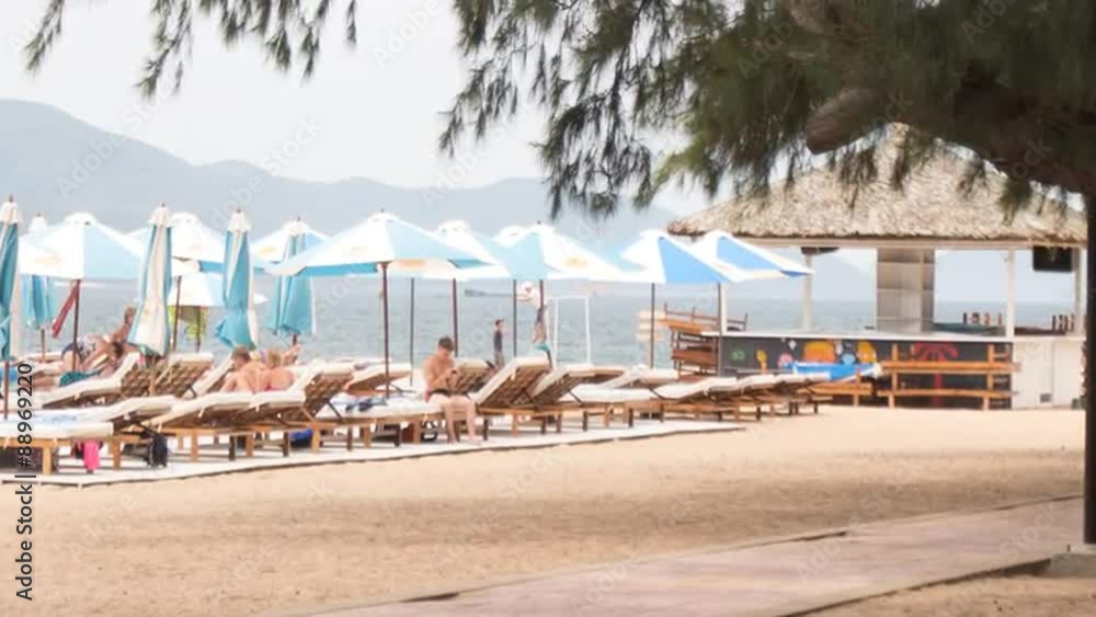guy walks speaks on phone on beach against sunbeds umbrellas guy walks speaks on phone on beach against sunbeds umbrellas