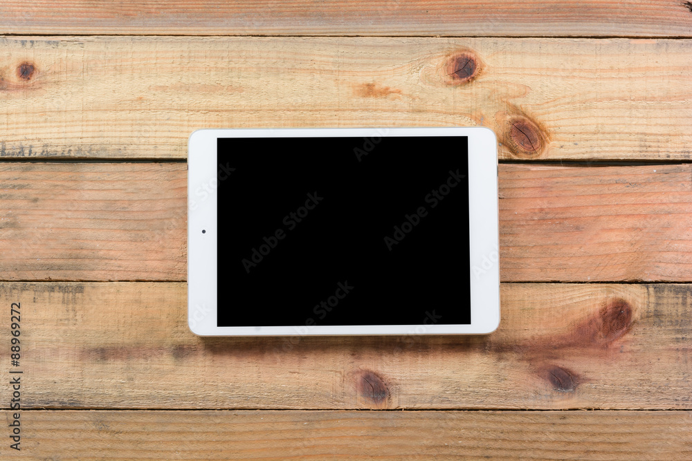 Tablet device on wooden workspace table Tablet device on wooden workspace table