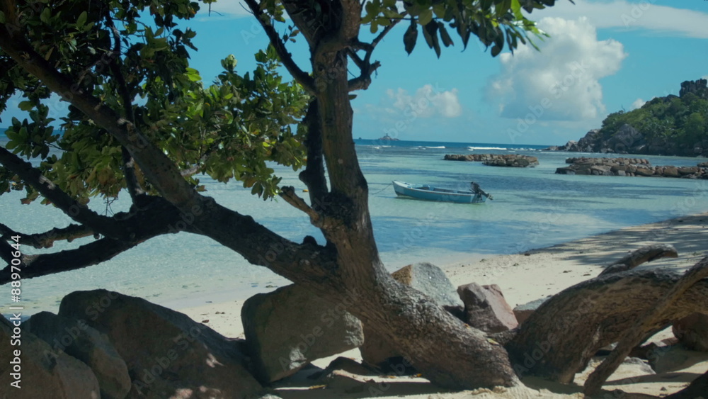 Boat on the beach in Seychelles La Digue island. A little blue boat in a lagoon in La Digue, Seychelles with view to Praslin. Boat on the beach in Seychelles La Digue island. A little blue boat in a lagoon in La Digue, Seychelles with view to Praslin.