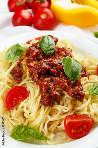 Spaghetti Bolognese on white plate, on color wooden background