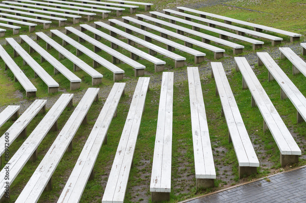 Rows of wooden benches on hillside of outdoor concert area