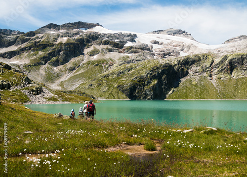 family on vacation hiking to blue lake in austrian alps with glacier view