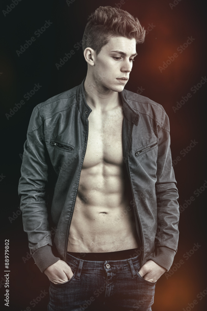 Handsome young man wearing leather jacket on naked torso Handsome young man wearing leather jacket on naked torso