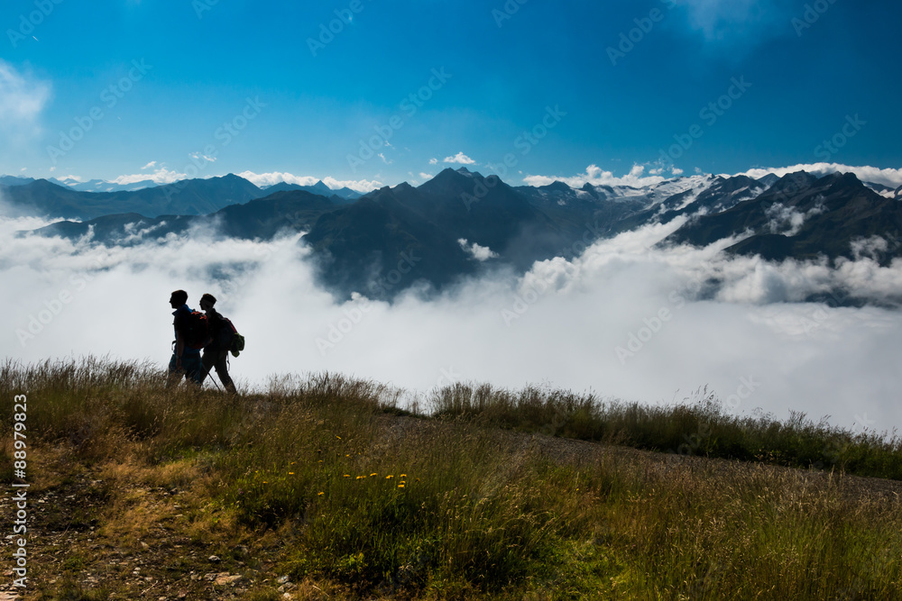 hikers silhouette in austrian alps with clouds