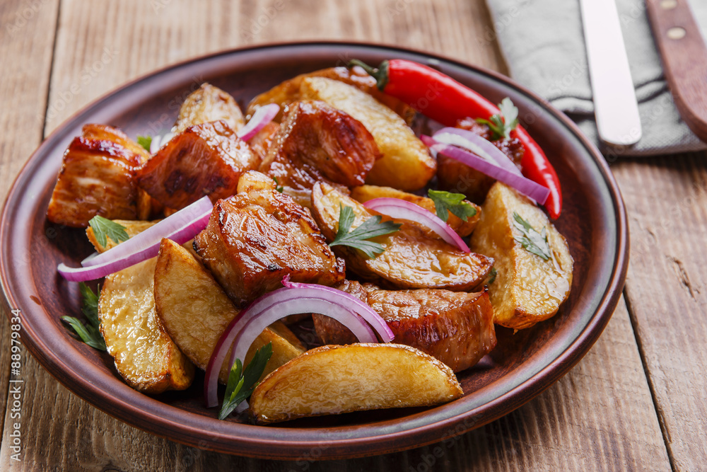 baked fried potatoes with meat  plate on  wooden surface