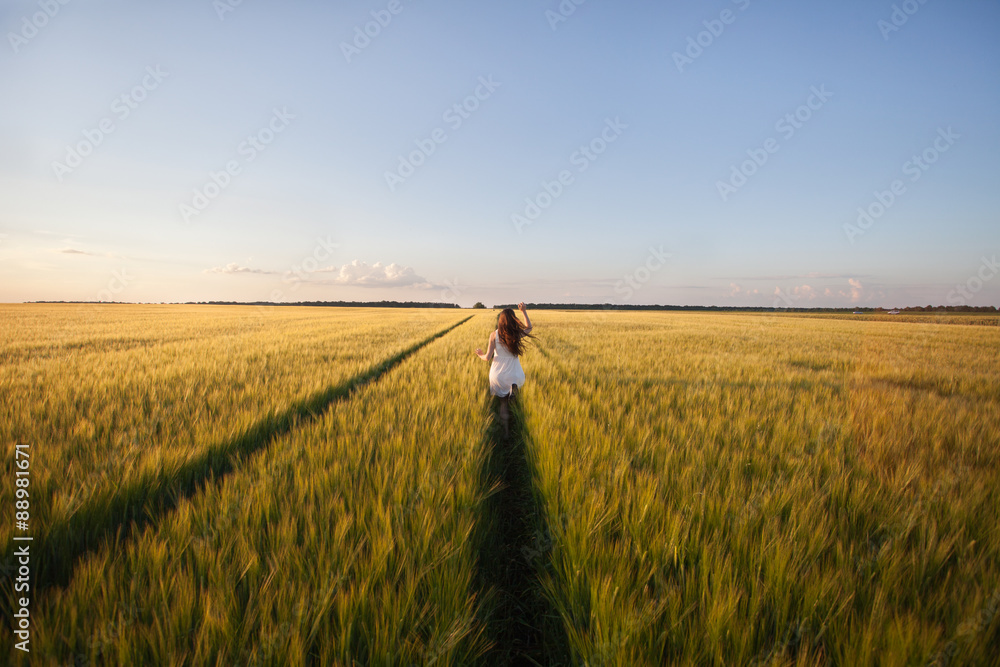 beautiful woman run away in yellow wheat field