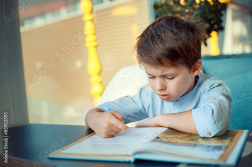 Boring and tired little boy reading book