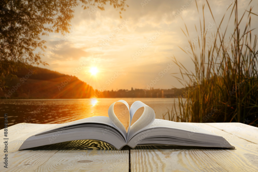 Fototapeta premium Open book on wooden table on natural blurred background. Heart book page. Back to school. Copy Space