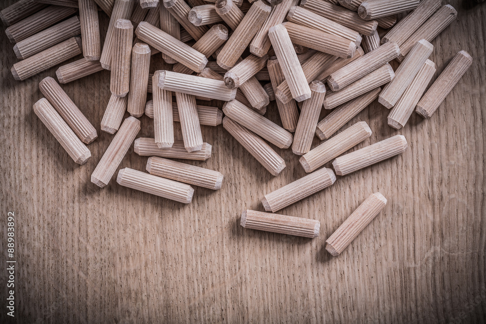 Collection of cylinder wooden dowel pins on wood board construct Collection of cylinder wooden dowel pins on wood board construct