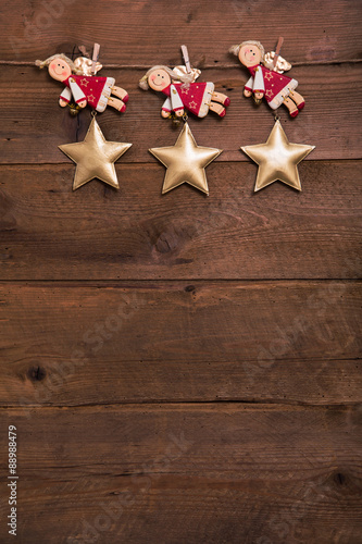 Holz Hintergrund alt im Hochformat mit Engel in rot als Dekoration mit drei Sternen.